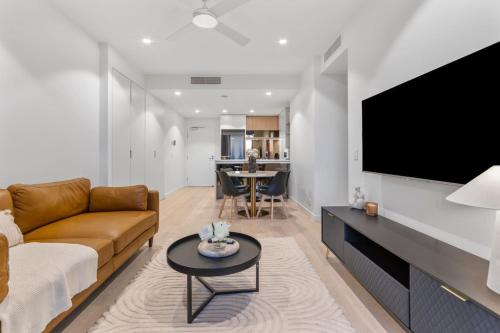 a living room with a couch and a flat screen tv at Luxurious 2 Bed Apartment with Pool, Sauna & Gym in Brisbane