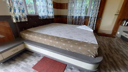 a small bed in a room with curtains at Orange Villa in Rinchingpong