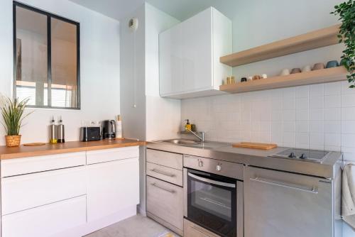 une cuisine avec des armoires blanches et un évier dans l'établissement OIQIA • Bucolie, à Rouen