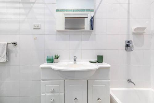 a white bathroom with a sink and a tub at Cosy 2 bedroom house in Melbourne