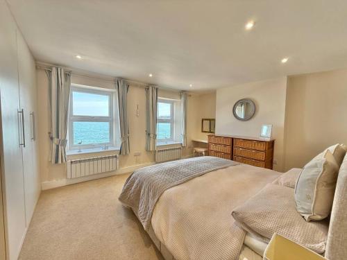 ein Schlafzimmer mit einem großen Bett und zwei Fenstern in der Unterkunft Goodwinds 4 bedroom beachside house in Torcross