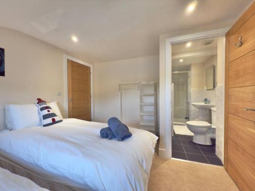 ein Schlafzimmer mit einem großen weißen Bett und ein Badezimmer in der Unterkunft Goodwinds 4 bedroom beachside house in Torcross