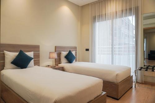 una camera d'albergo con due letti e una finestra di Flamant Rose Appart Hotel a Tangeri