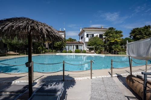 a large swimming pool with chairs and an umbrella at Villa Carlotta Jesolo Lido in Lido di Jesolo