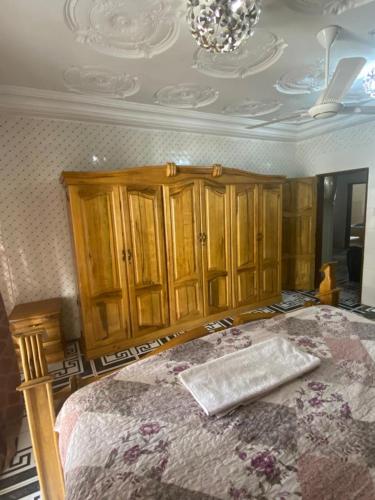 a bedroom with a bed with wooden cabinets and a ceiling at Dalal Jamu in Serekunda