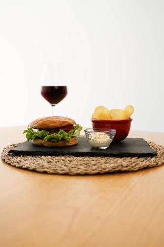 a sandwich on a black tray with a glass of wine at Marinhas Bed & Breakfast in Esposende