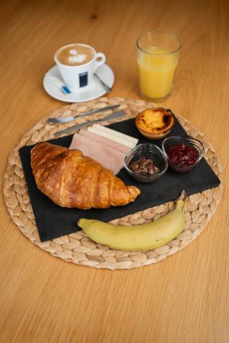 a plate of breakfast food with a banana and a cup of coffee at Marinhas Bed & Breakfast in Esposende