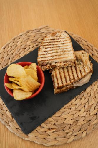 a sandwich and chips on a plate with a bowl of chips at Marinhas Bed & Breakfast in Esposende