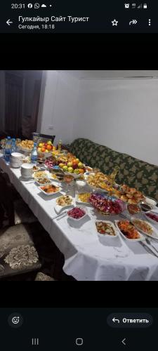 a long table with many plates of food on it at SALKYN YURT guest house in Kyzart