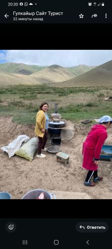 two women standing around a grill in a field at SALKYN YURT guest house in Kyzart