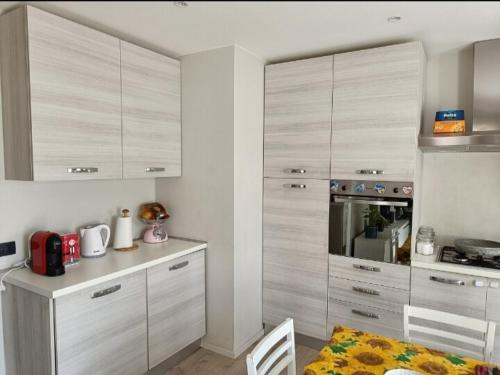 a kitchen with white cabinets and a table and a dining room at Appartamento tranquillo Ellis Home in Morbegno
