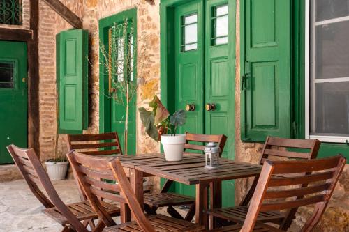 a wooden table and chairs with green doors at The Psyri Collection in Athens