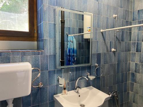 a blue tiled bathroom with a sink and a mirror at Stone & Sea house in Valdanos
