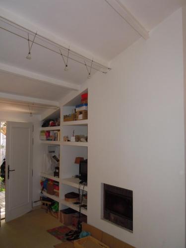 Elle comprend un salon doté d'un mur blanc et d'une cheminée. dans l'établissement Charmante Maison Saint-Martin-de-Ré, à Saint-Martin-de-Ré