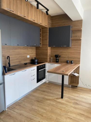 a kitchen with white cabinets and a wooden table at Hira apartment in Golem