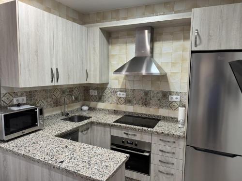 a kitchen with white cabinets and a stainless steel refrigerator at Apartamentos La Gruta de Aracena con vistas in Aracena