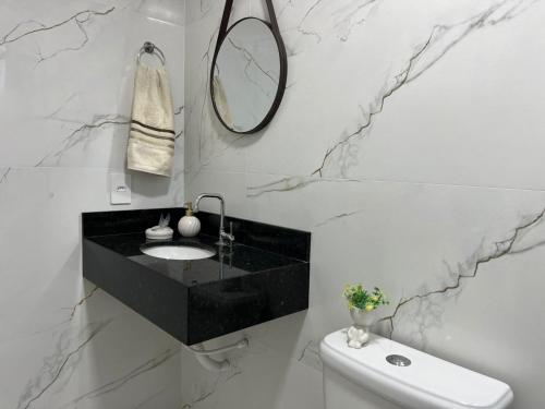 a black and white bathroom with a sink and a mirror at Apto Vida Boa 2 - 250m do mar in Palhoça