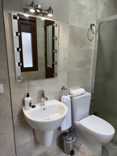 a bathroom with a sink and a toilet and a mirror at Apartamentos La Gruta de Aracena con vistas in Aracena