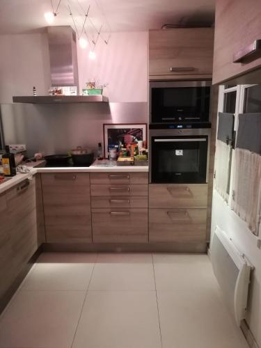 une cuisine avec des armoires en bois et un gros électroménager dans l'établissement Charmante Maison Saint-Martin-de-Ré, à Saint-Martin-de-Ré