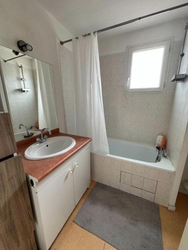 La salle de bains est pourvue d'un lavabo, d'une baignoire et d'une fenêtre. dans l'établissement Ernest-Toulouse - LB - T2 bien placé, à Toulouse