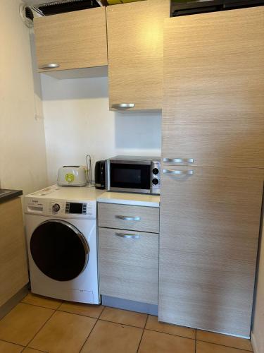une cuisine avec un lave-linge et un four micro-ondes sur un comptoir dans l'établissement Ernest-Toulouse - LB - T2 bien placé, à Toulouse