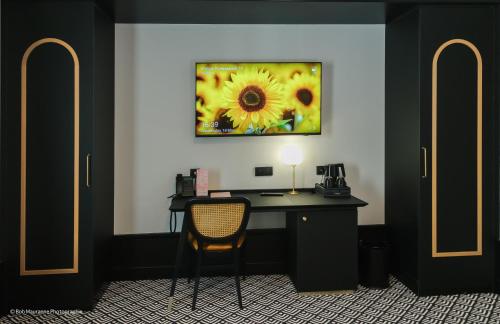 a desk with a chair and a picture of a sunflower at Hôtel et Restaurant Le Regina in Le Puy en Velay