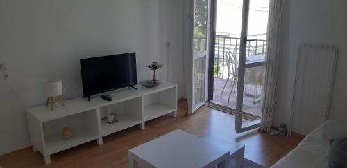 a living room with a flat screen tv on a white cabinet at Oleander Apartments in Selce