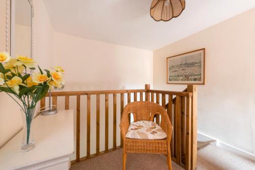 a room with a chair and a vase of flowers at Tanglewood Cottage - Lancombes House in Powerstock
