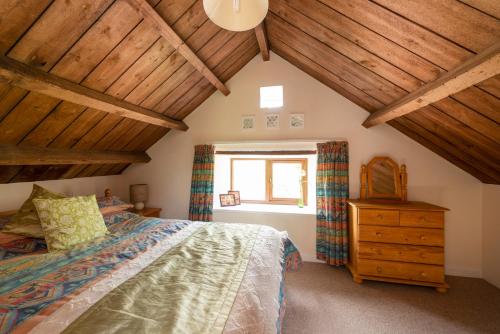 a bedroom with a bed and a wooden ceiling at Tanglewood Cottage - Lancombes House in Powerstock