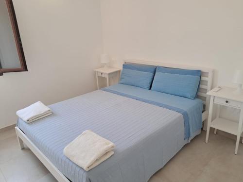 a white bedroom with a blue bed with blue pillows at Agriturismo Tenuta La Siesta in Gallipoli