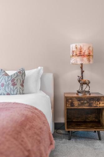 a lamp on a wooden table next to a bed at Luxe 5 Bedroom Guardbridge House - St Andrews in St. Andrews