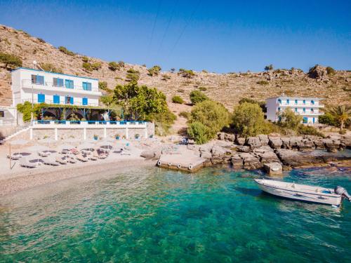 a boat in the water next to a beach at Finikas Resort Sfakia - Seaside Rooms in Loutro