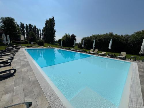 a large swimming pool with lounge chairs and umbrellas at Green Garda Holidays - Garda Lake in Castelnuovo del Garda