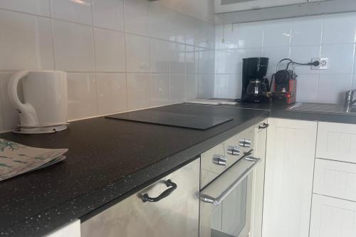 une cuisine avec des armoires blanches et un comptoir noir dans l'établissement Between Sky and Waves, à Aresquies