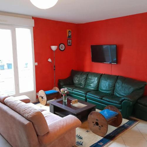 - un salon avec un canapé vert et des murs rouges dans l'établissement Maison familiale charmante à Ingrandes, à Ingrandes