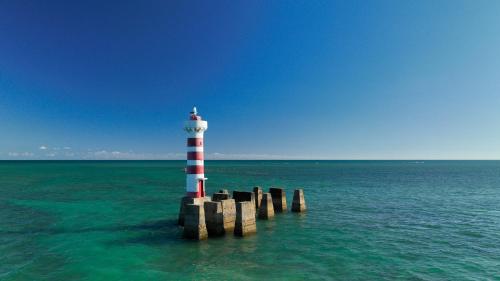 a red and white lighthouse in the middle of the ocean at Salinas Maceio All Inclusive Resort in Maceió