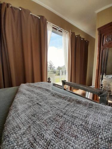 a bedroom with a large bed with a large window at Aroma de la sierra in Villa Serrana