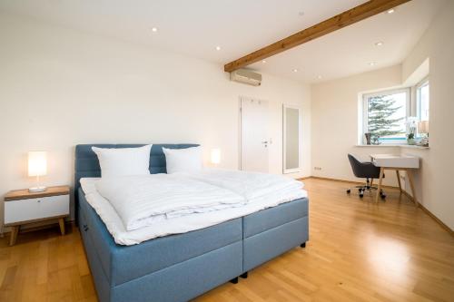 a bedroom with a blue bed and a desk at Seaside House - Ferienhaus mit privatem Bootsanleger, Terrasse und Wellness-Komfort direkt am Wasser in Malchow