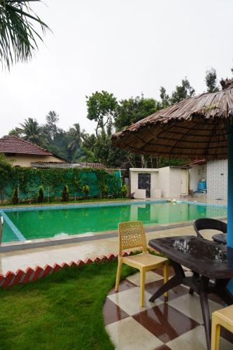 a patio with a table and chairs next to a swimming pool at LAKE VIEW Chikkamagaluru in Chikmagalūr