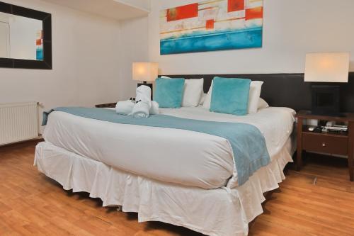 a bedroom with a large bed with two stuffed animals on it at Hotel Boutique Trinidad in Viña del Mar
