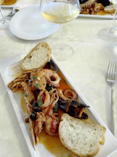 a plate of food with shrimp and bread and a glass of wine at Locanda San Giorgio in Termoli