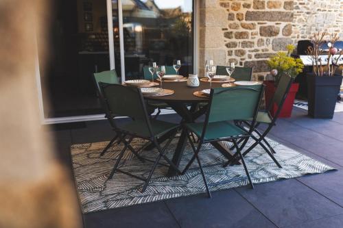 une table en bois avec des chaises vertes sur la terrasse dans l'établissement La maison de marie, à Epiniac
