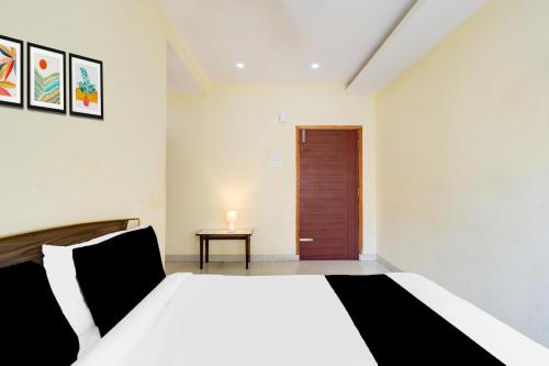 a bedroom with a white bed and a wooden door at Hotel O Sangareddy Formerly Ragas Grand in Patancheru