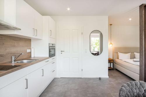 a white kitchen with a sink and a bedroom at Meer in Sicht in Eckernförde
