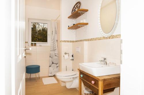 a bathroom with a sink and a toilet and a mirror at Ferienwohnung Kunterbunt Eckernförde in Eckernförde