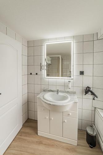 a white bathroom with a sink and a mirror at Hotel Seepferdchen Zimmer 6 Eckernförde Self-Check-In in Eckernförde