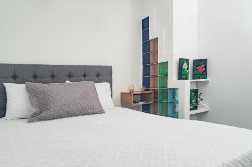 a bedroom with a white bed with a gray pillow at Innovar Casa Hostal in Bogotá