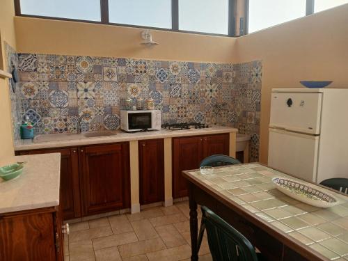 a kitchen with a table with a microwave and a refrigerator at Alykè Appartamenti Vacanze Macari in Macari