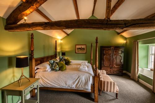a bedroom with green walls and a bed and a table at Queen's Head Askham in Penrith
