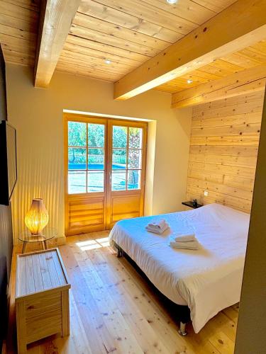 une chambre avec un grand lit et une grande fenêtre dans l'établissement Maison en pierre, à Grignan